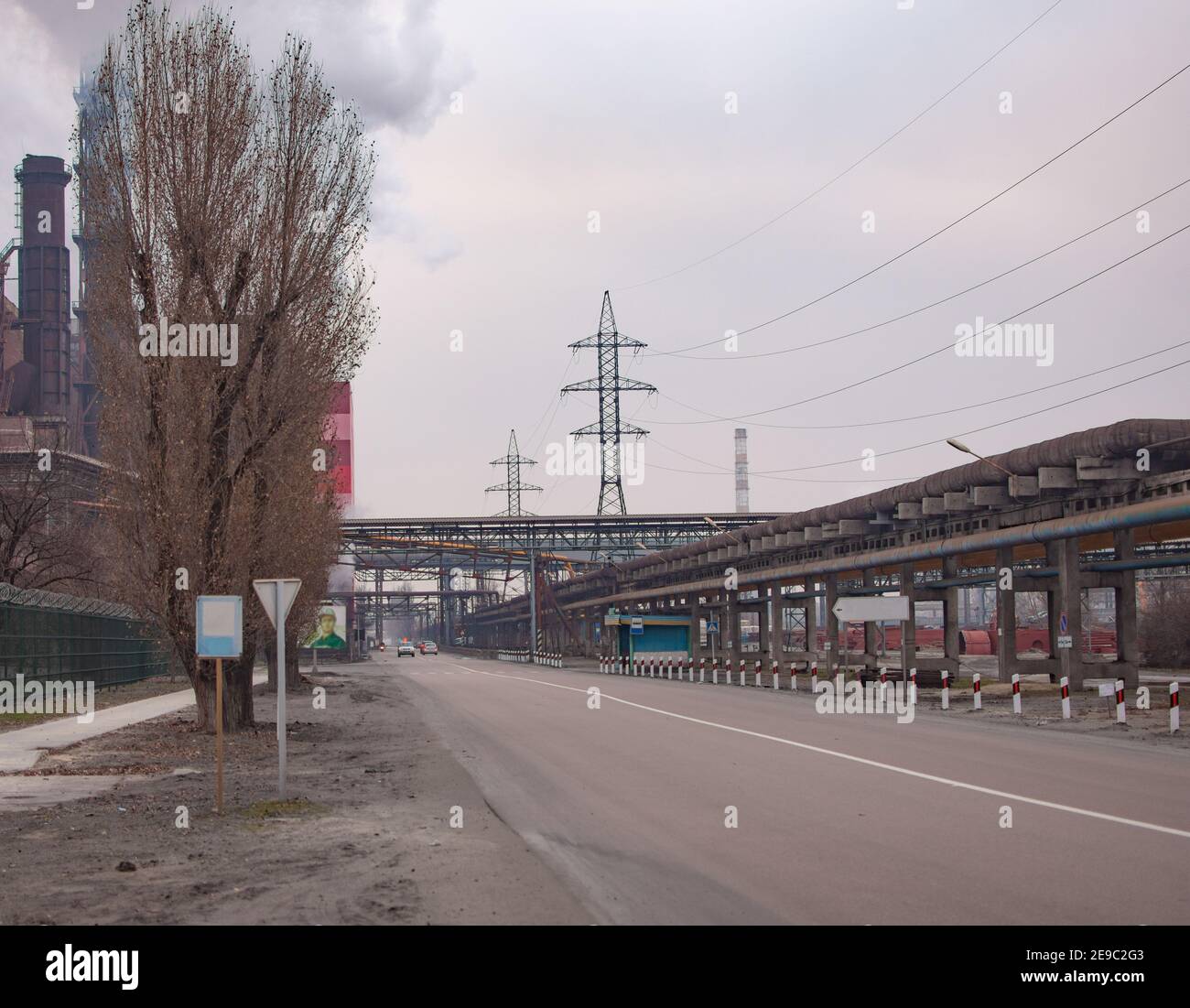 Una strada su un grande sito industriale. Tubazioni, linee elettriche. Foto Stock