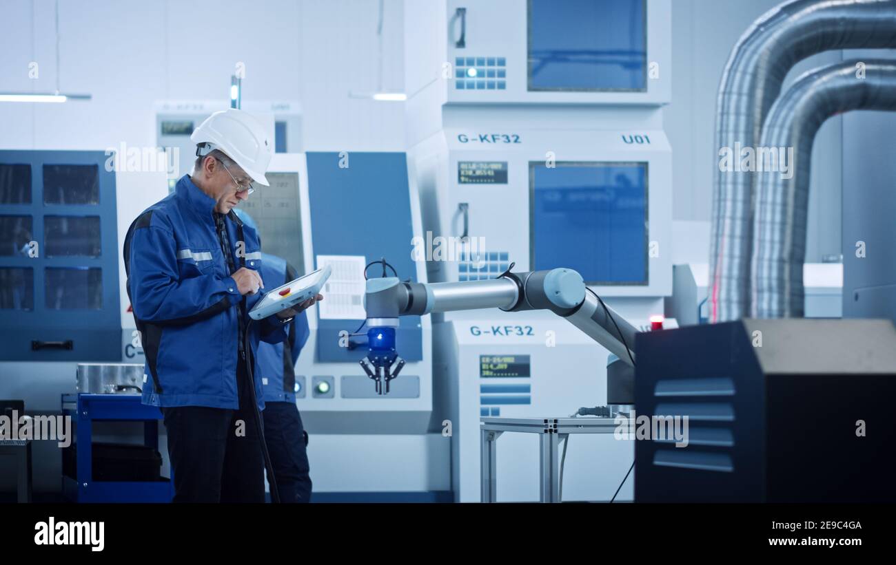 Capo ingegnere che indossa giubbotto di sicurezza e cappello duro, utilizzare il tablet digitale in fabbrica moderna, ottimizzando la linea di produzione. Struttura industriale: Professionisti Foto Stock