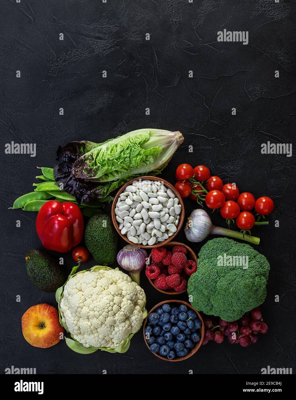 Cibo sano di fondo, prodotti dietetici alla moda a base di piante - verdure fresche crude, frutti di bosco e fagioli. Foto Stock