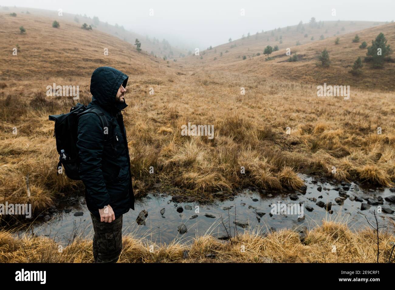 Giovane uomo che esplora la natura in una mattinata invernale bagnata le montagne Foto Stock