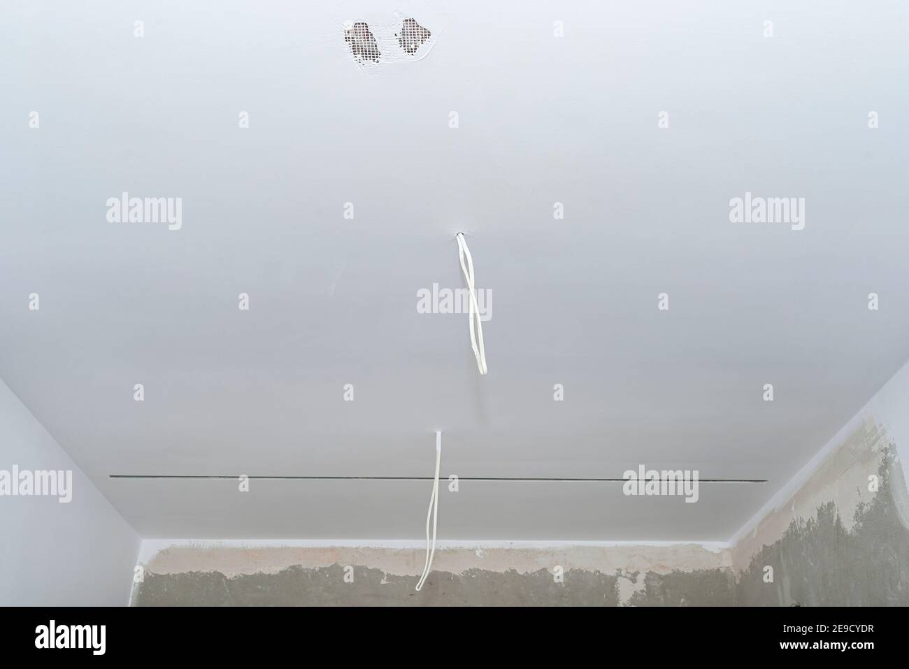 Due cavi provenienti dall'illuminazione dall'alto che sporgono dai soffitti senza lampadine. Foto Stock