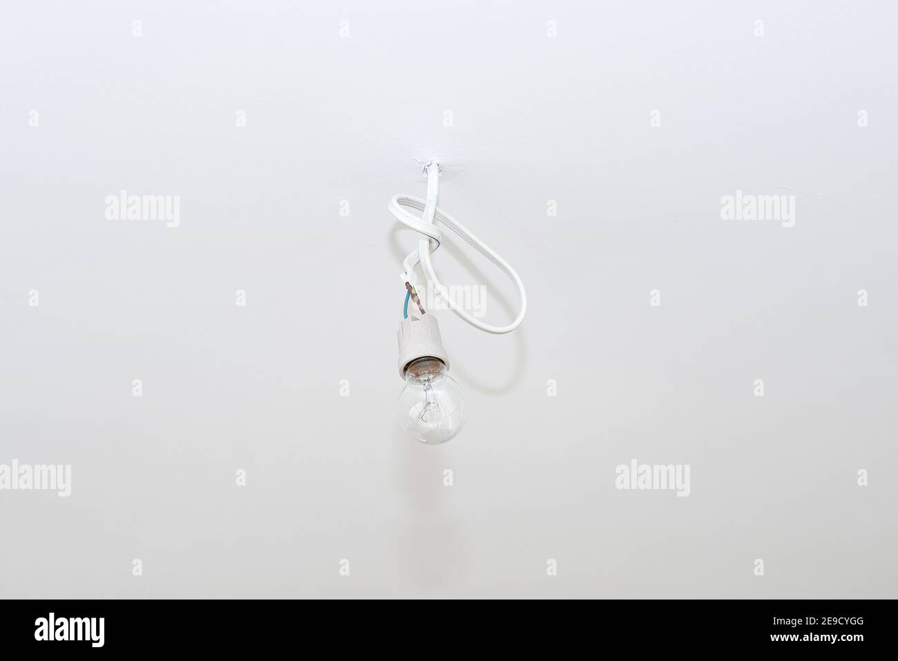 Lampada appesa a un cavo che sporge dalla parete con una punta in ceramica. Foto Stock