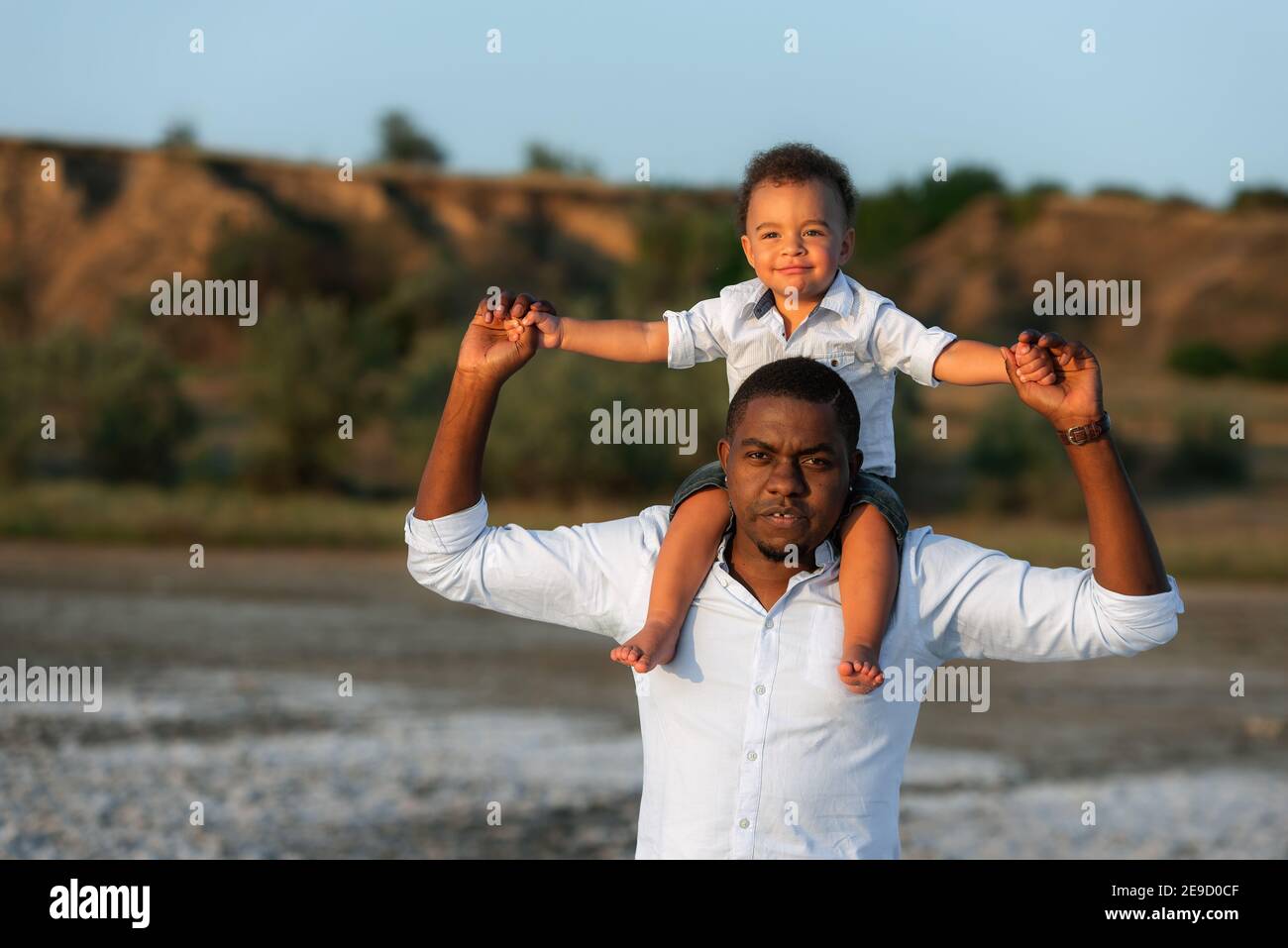 Dolci momenti di paternità concetto. Eccitato l'uomo afroamericano che dà cavalcata piggyback al figlio di corsa abbastanza misto. Divertimento durante il weekend Foto Stock