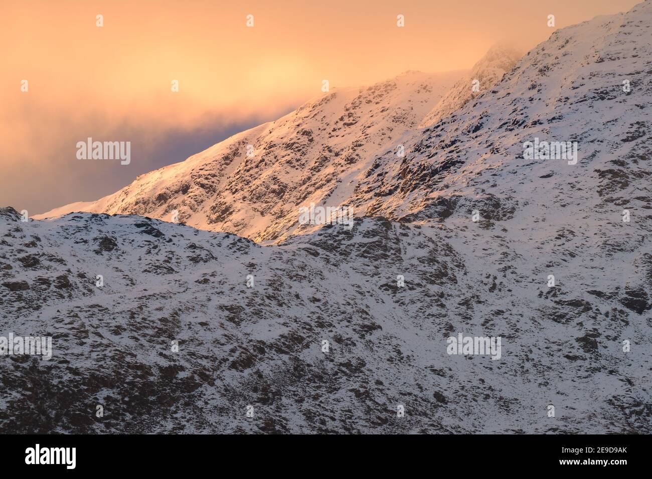 Mattina luce del sole sulle montagne innevate invernali nel Lake District con belle nuvole. Foto Stock