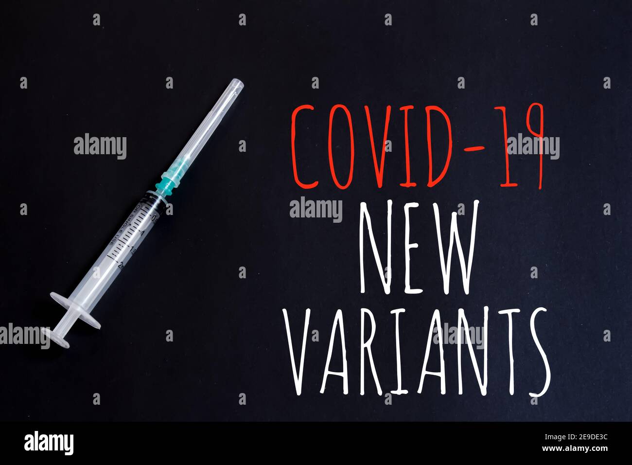 Covid-19 Nuova variante testo e siringa medica su sfondo nero. Concetto di coronavirus mutato. Foto Stock