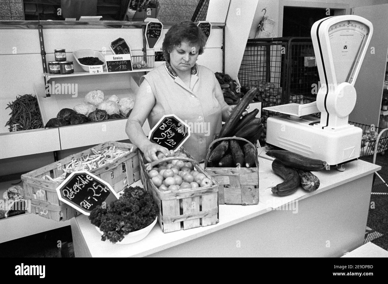30 novembre 1984, Sassonia, Laußig: Presso lo stand frutta e verdura del grande magazzino nella cittadina di Laußig (quartiere di Eilenburg) nel 1985, i pomodori, i fagioli, i cetrioli, le mele, l'uva sultanina, il prezzemolo, il cavolo bianco, il cavolo rosso e le patate sono tra i prodotti in vendita. Data esatta della registrazione non nota. Foto: Volkmar Heinz/dpa-Zentralbild/ZB Foto Stock