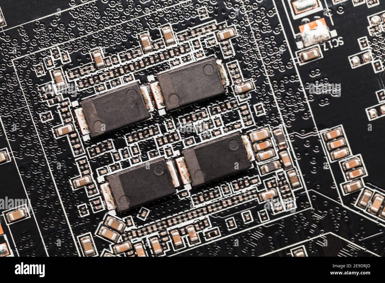 Macrofotografia su scheda a circuito stampato nera con microchip e condensatori Foto Stock