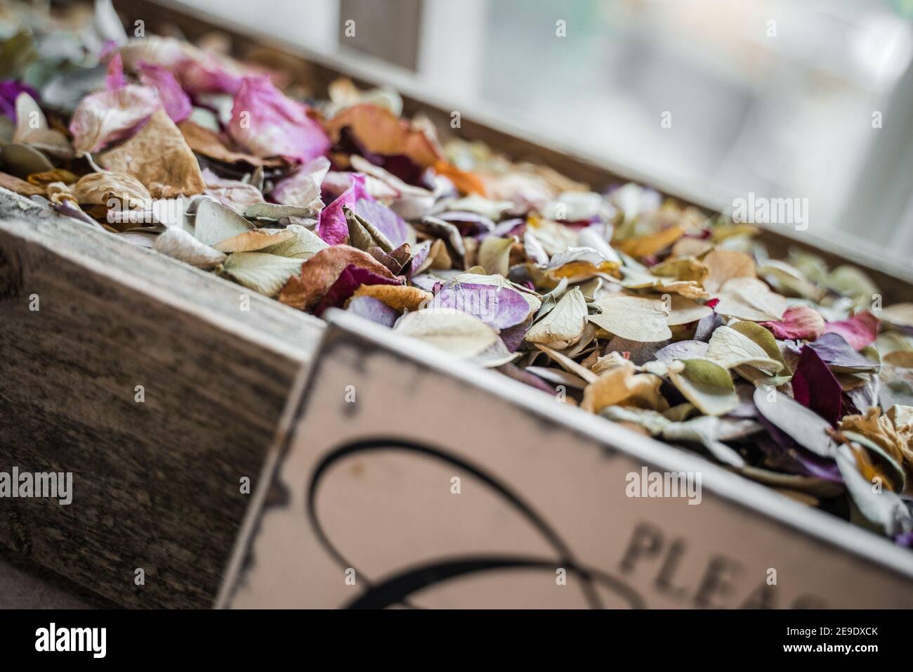 Primo piano di legno rustico shabby elegante scatola riempito con confetti fatti di petali di fiori naturali tutti i colori vibranti differenti con l'accesso davanti Foto Stock