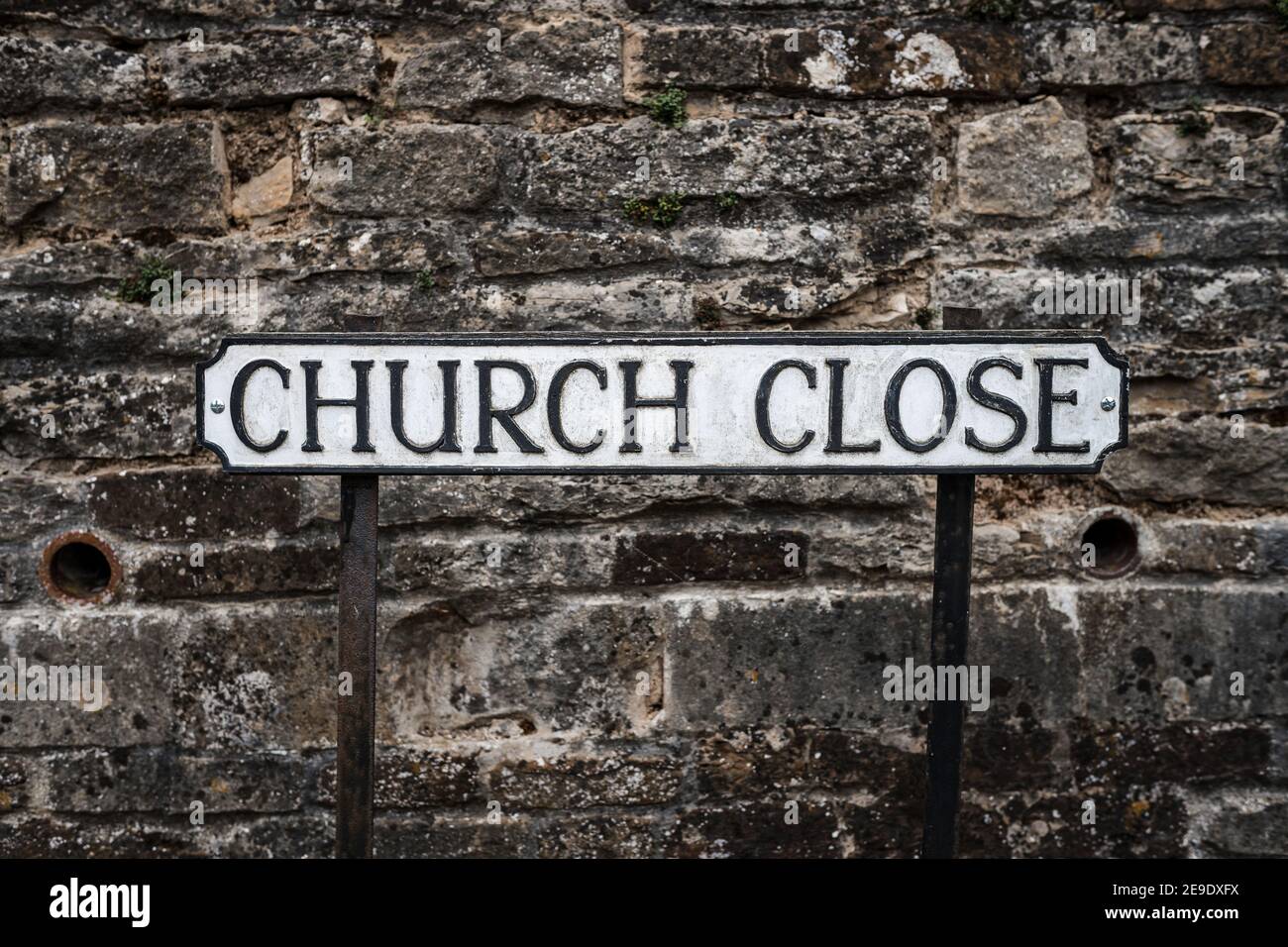Tradizionale inglese Church Street indirizzo postale segno nero su piastra in metallo bianco in piedi sul sentiero dei piedi della strada con muro di pietra dietro la chiesa Foto Stock
