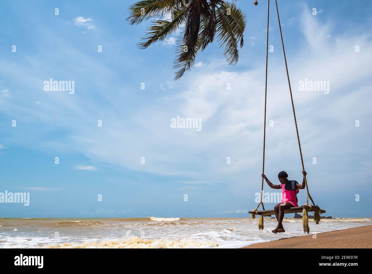 Donna africana seduta al mare su una sedia sospesa. Axim Ghana West Africa Beach 2018 novembre 2 Foto Stock