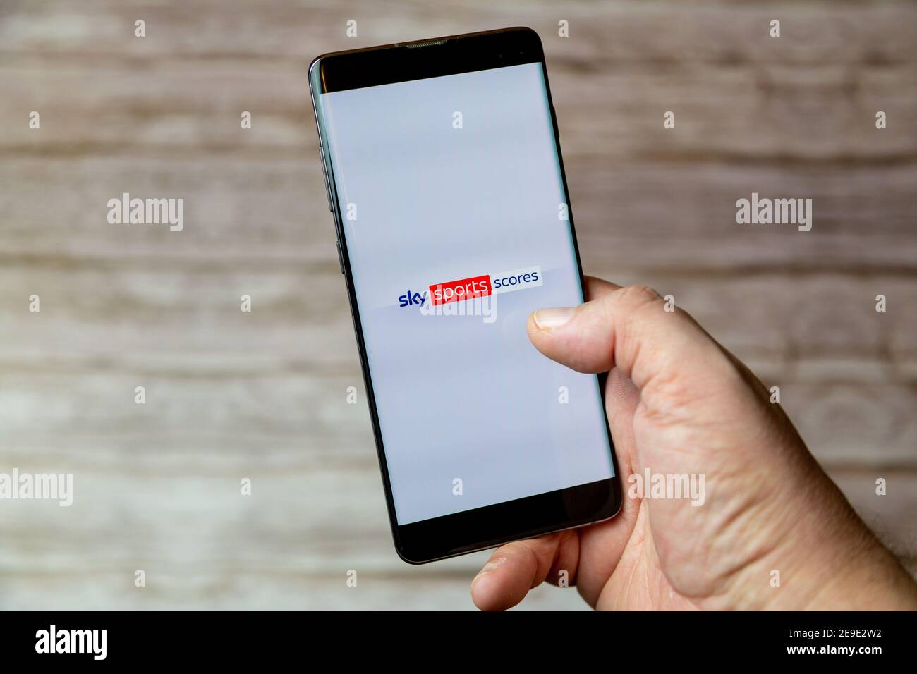 Una mano che tiene un telefono cellulare o cellulare con L'app Sky SPORTS Live Spartiti sullo schermo Foto Stock