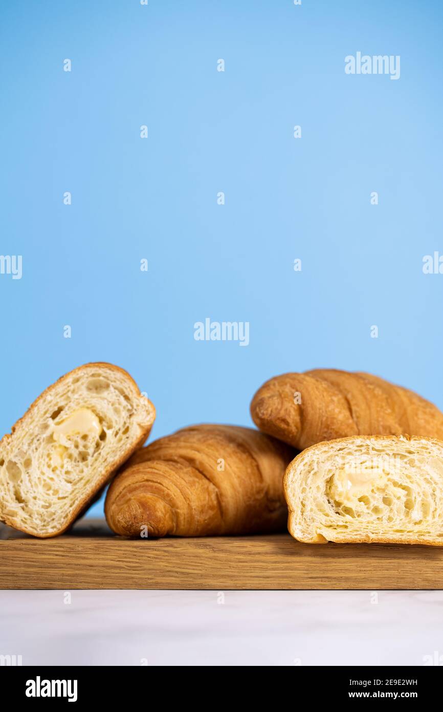 croissant freschi su tavola di legno. Сroissants su sfondo blu. Foto Stock