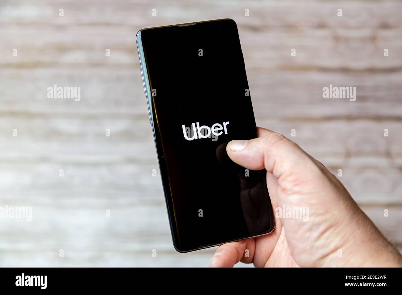 Una mano che tiene un telefono cellulare o cellulare con L'app Uber sullo schermo Foto Stock