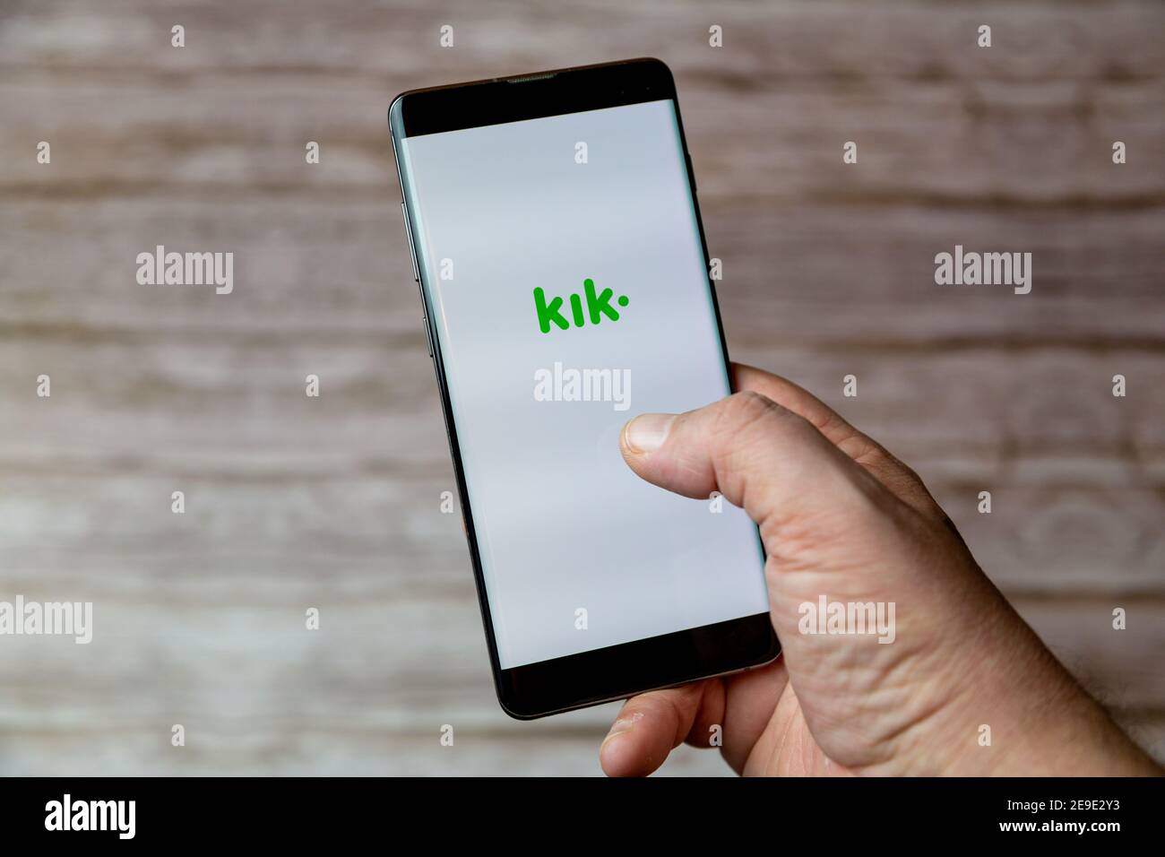 Una mano che tiene un telefono cellulare o un telefono cellulare con L'app di messaggistica KIK sullo schermo Foto Stock