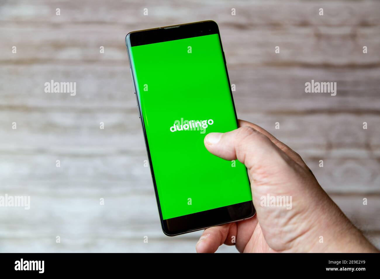 Una mano che tiene un telefono cellulare o cellulare con L'applicazione della lingua Duolingo sullo schermo Foto Stock