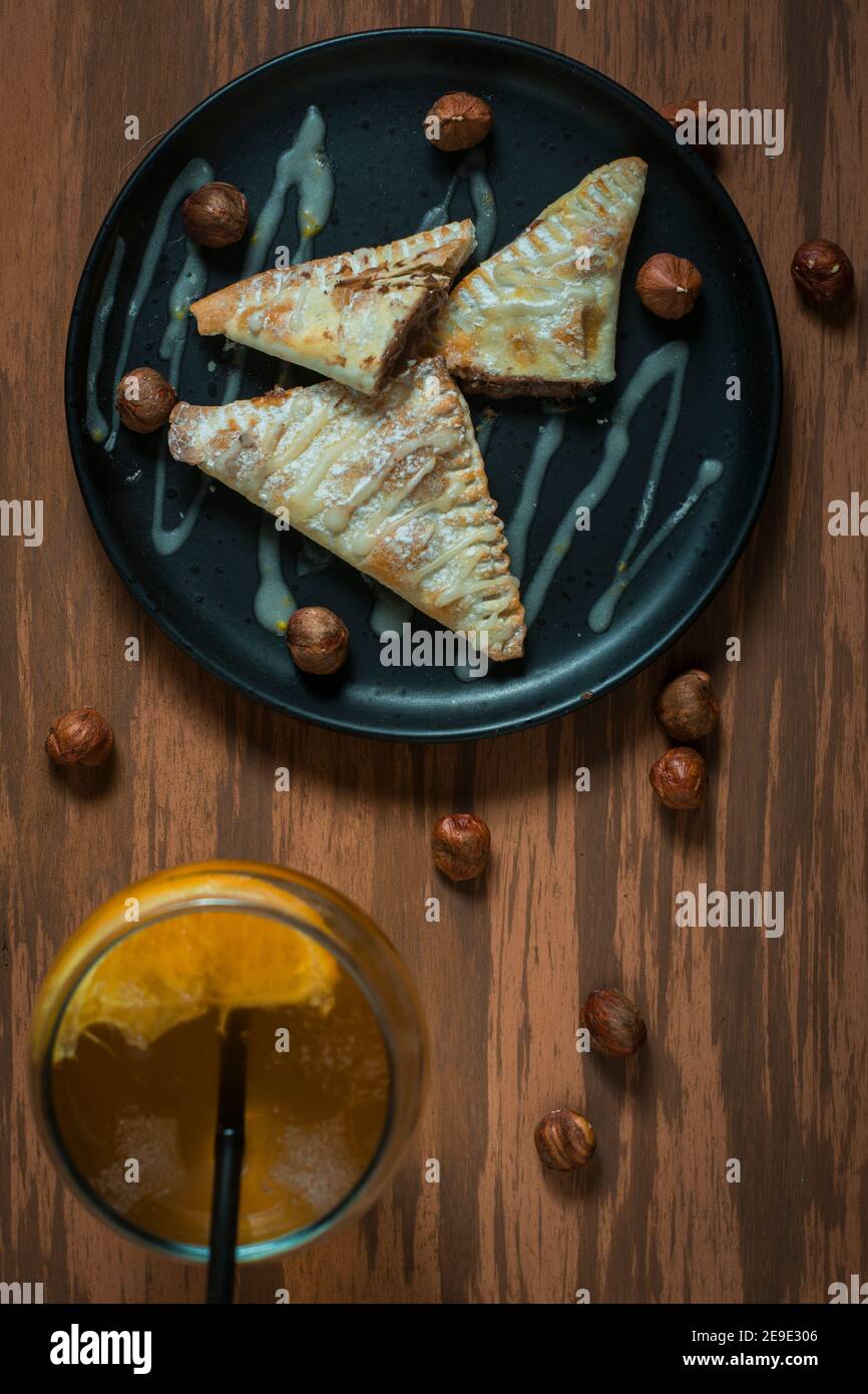 Nutella mano torte su un piatto nero con alcuni bicchieri liquori su un tavolo di legno. Foto Stock