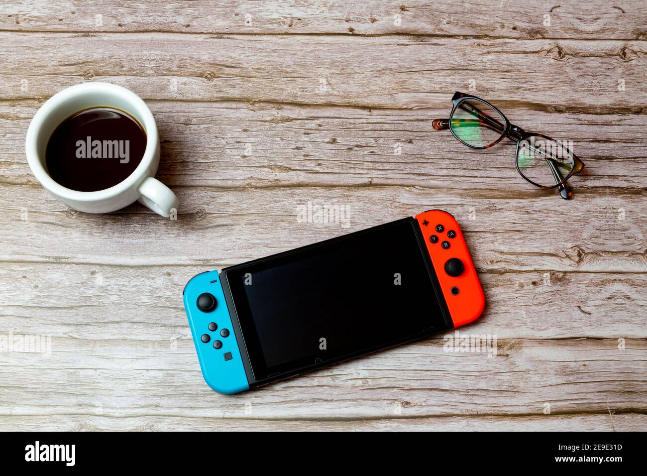 Una console di gioco Nintendo Switch disposta su una scrivania o. tavolo accanto a un caffè e bicchieri Foto Stock