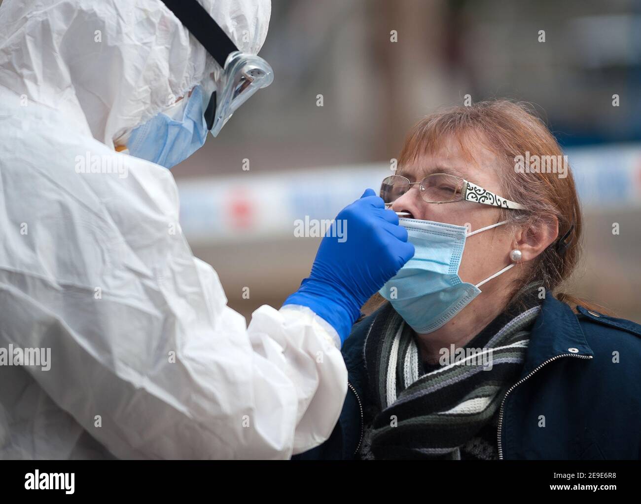 Malaga, Spagna. 04Feb 2021. Un operatore sanitario che indossa una tuta per dispositivi di protezione individuale (DPI) raccoglie campioni di swap da una donna all'esterno di una stazione di test del coronavirus durante un'enorme prova della covid-19 a Plaza Limeno nel centro della città. A causa dell'elevato tasso di infezioni da coronavirus nella capitale di Malaga, circa 1.600 volontari sono stati selezionati dalle autorità sanitarie per partecipare a un test casuale per la covid-19 dell'antigene. Credit: SOPA Images Limited/Alamy Live News Foto Stock