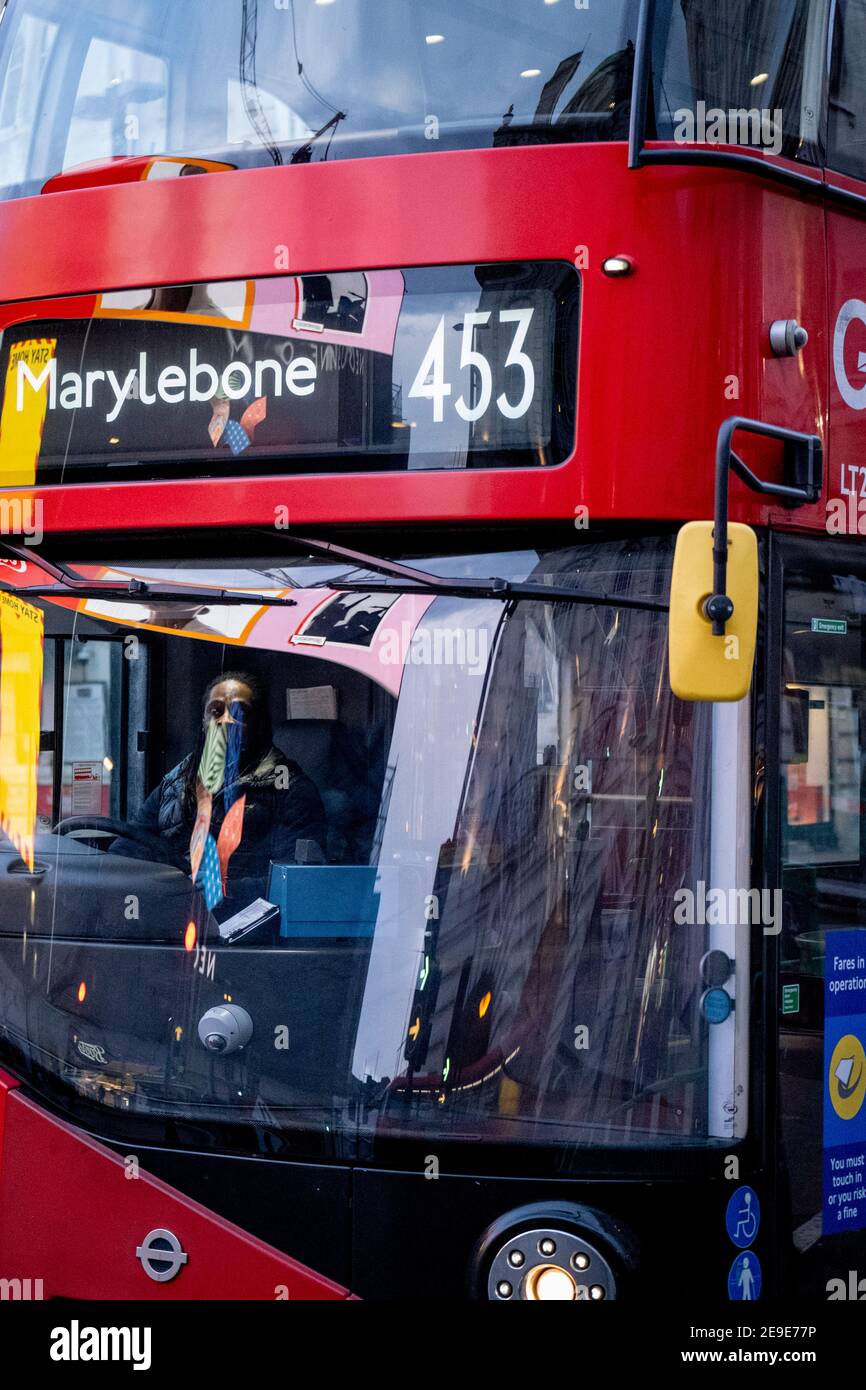 Visto riflesso nel parabrezza di un autobus di passaggio, un annuncio del governo NHS (National Heath Service) mostra il volto di un paziente di Covid, esortando i londinesi a rimanere a casa e a non correre rischi o piegare le regole durante il terzo blocco della pandemia di Coronavirus, A Piccadilly Circus nel West End della capitale, il 3 febbraio 2021, a Londra, Inghilterra. Foto Stock