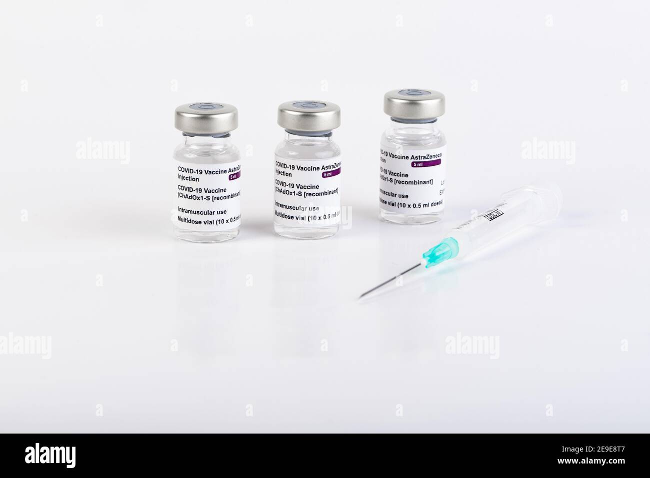 Tre flaconcini di vaccino Covid-19 con fondo bianco e una siringa per iniettare medici e persone a rischio. Trattamento di vaccinazione SARS-COV-2 Foto Stock