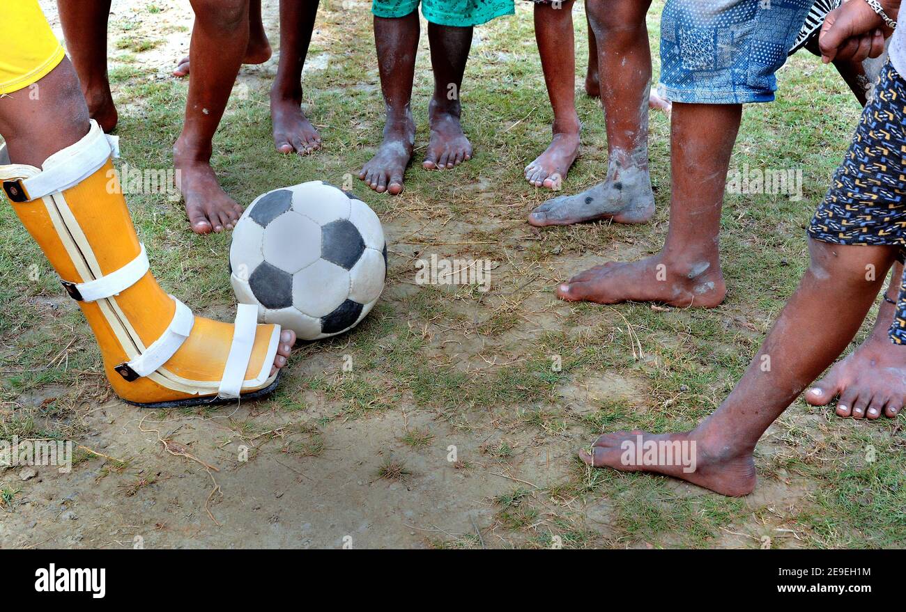 I bambini del villaggio remoto giocano a calcio nel campo da gioco del Bengala Occidentale in India. Foto Stock