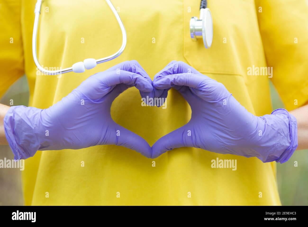 Primo piano il personale sanitario irriconoscibile con uniforme, guanti e stetoscopio formando un cuore con le mani. Concetto di assistenza sanitaria. Foto Stock