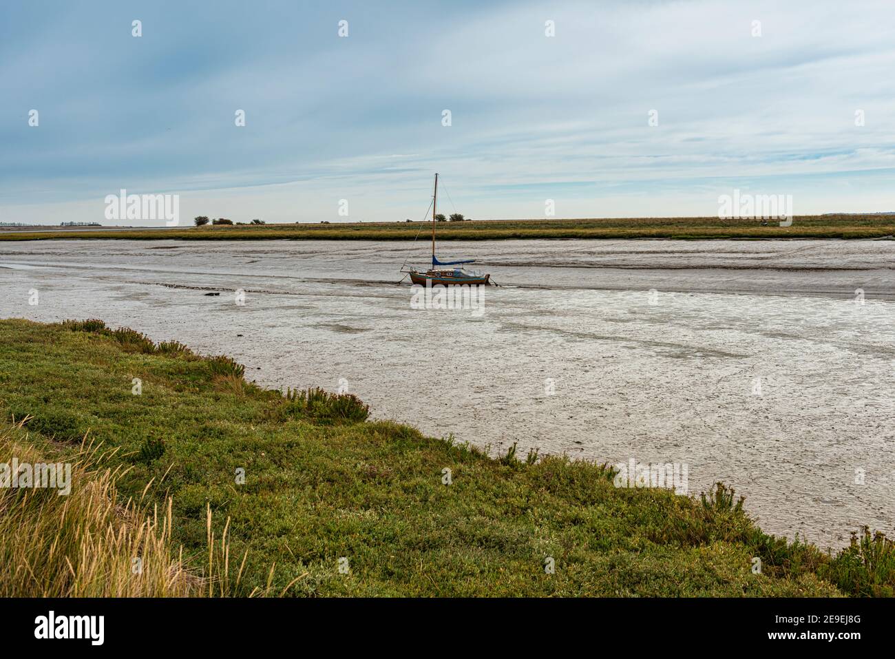 Barca sull'estuario della Swale a bassa marea a Oare vicino a Faversham in Kent, che domina l'isola di Sheppey Foto Stock