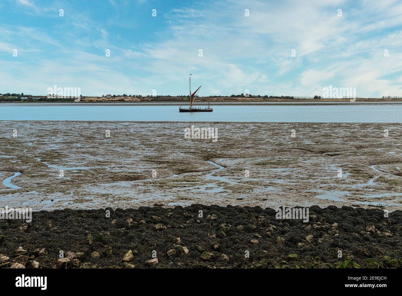 Barca a vela sull'estuario della Swale a bassa marea a Oare vicino a Faversham in Kent, che domina l'isola di Sheppey Foto Stock