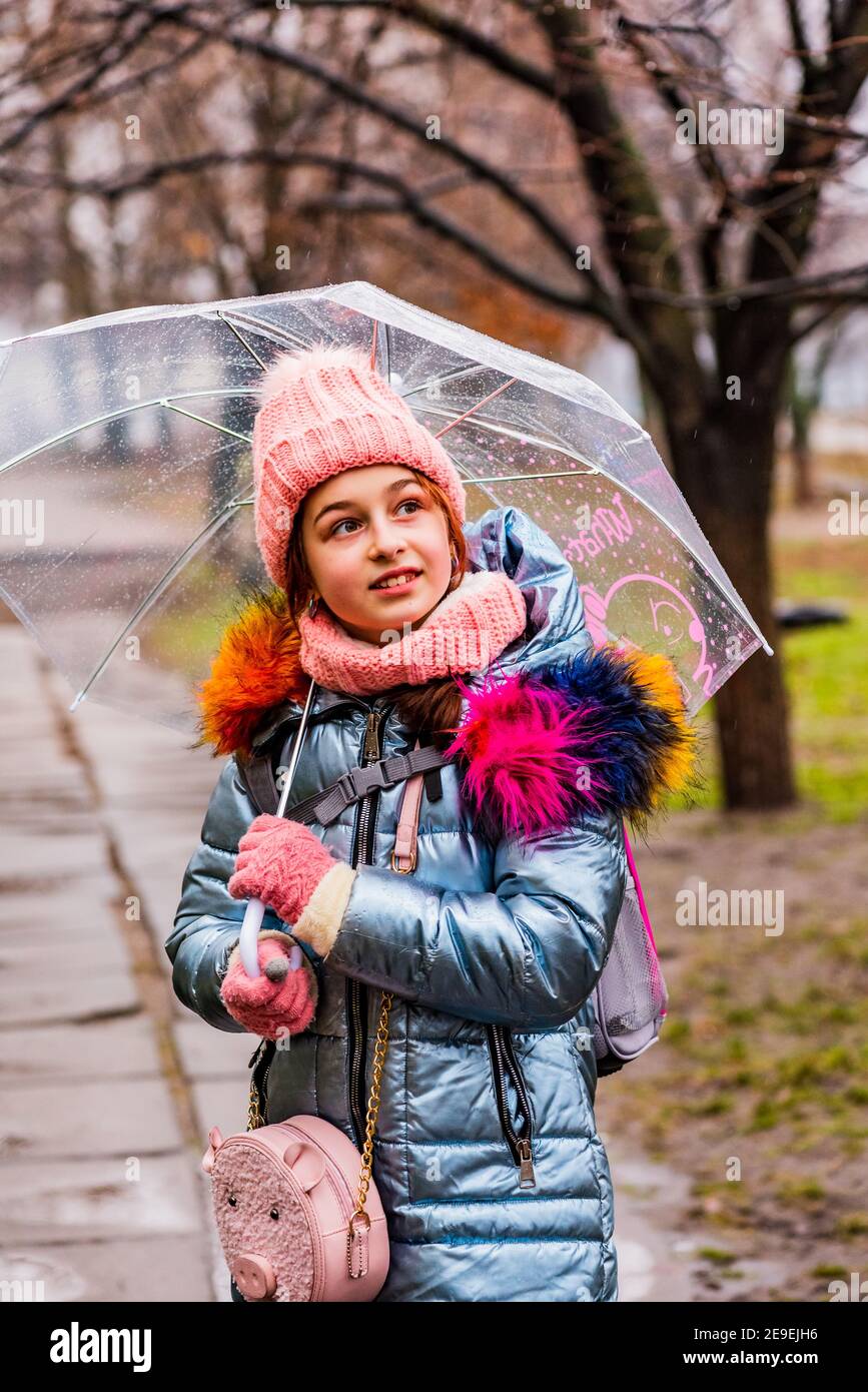 ragazza in giacca con ombrello trasparente sotto la pioggia al freddo.  Adolescente sotto un ombrello Foto stock - Alamy