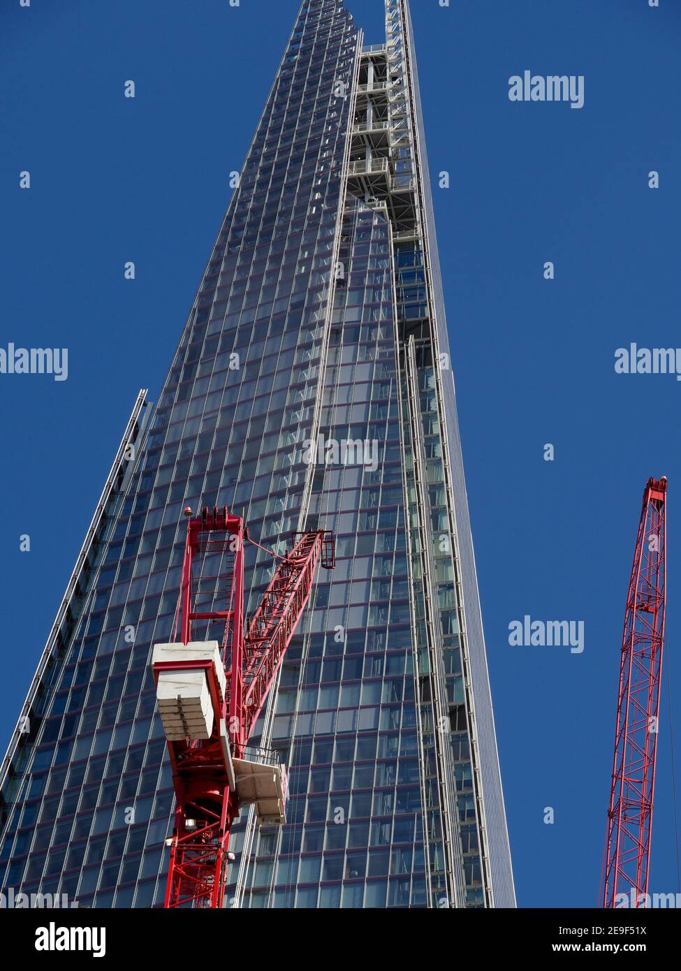 Vista dell'edificio Shard contro un cielo blu profondo con gru a torre rossa in primo piano Foto Stock