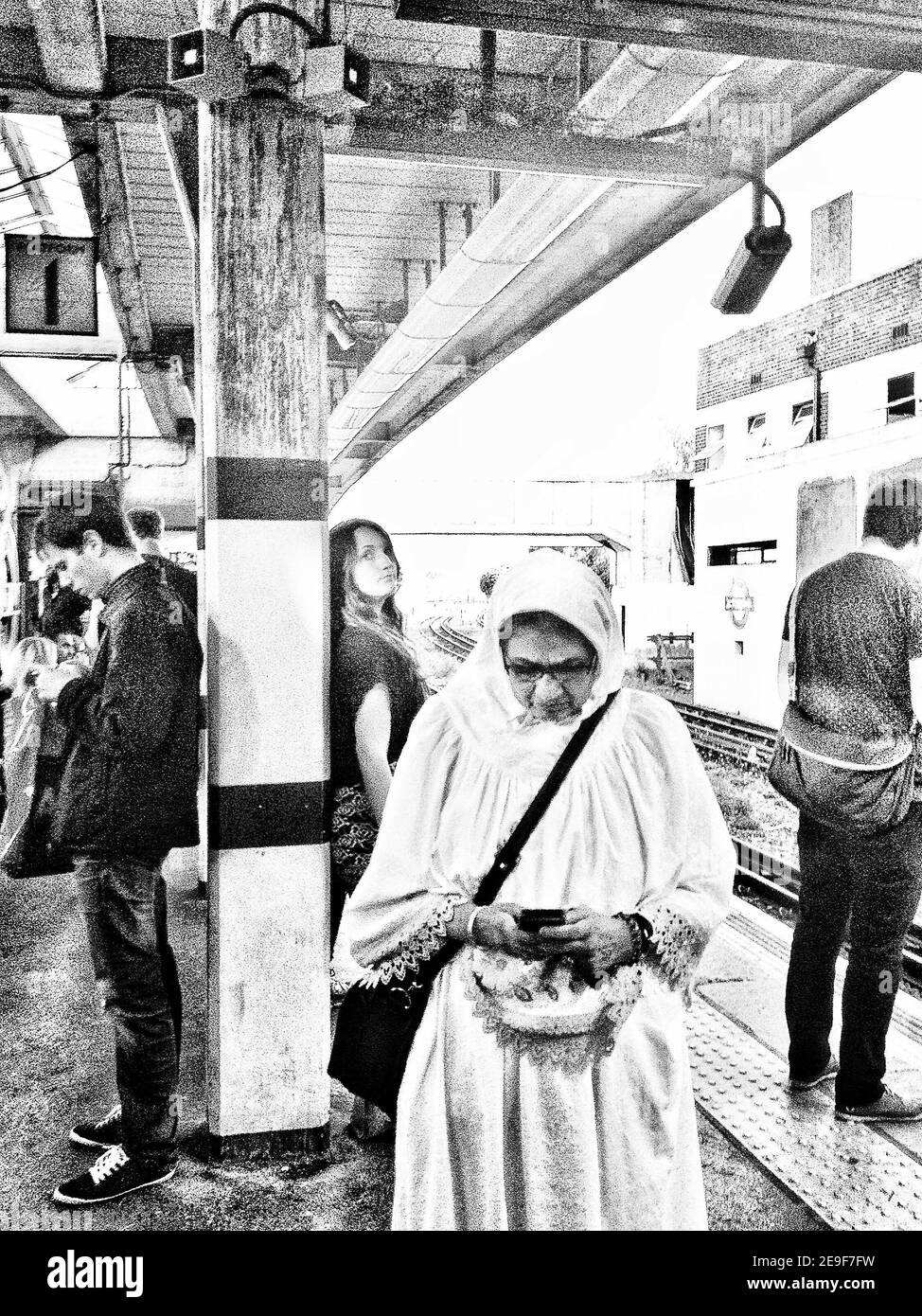 Pendolari in attesa di un treno alla stazione della metropolitana Northfields di Londra (parte di una serie di immagini acquisite ed elaborate su IPhone) Foto Stock