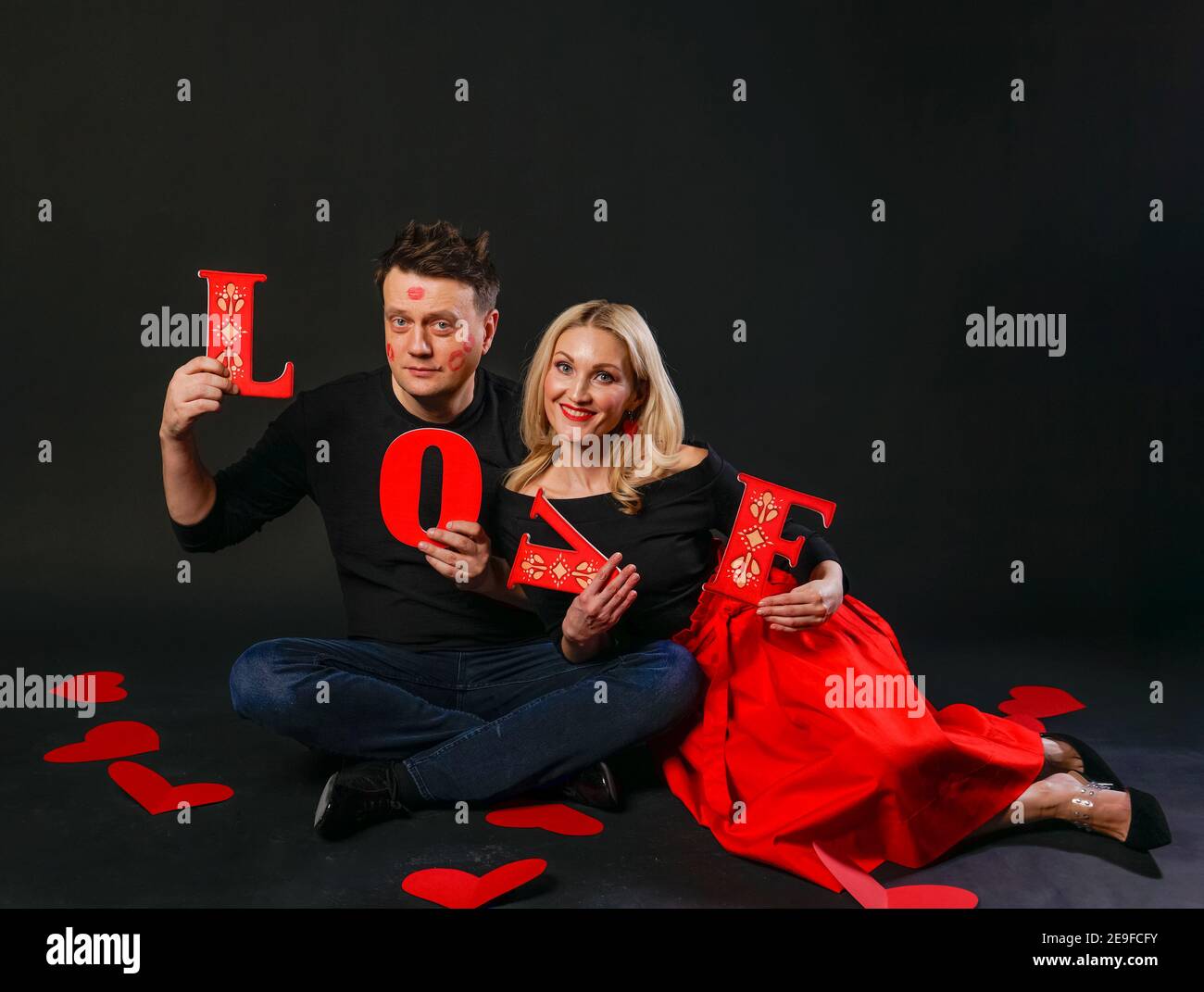 La famiglia tiene felice la parola AMORE, cuore di San Valentino, sul pavimento cuori sposati matrimonio. Ispirazione per la luna di miele. Formula di amore, impegno i Foto Stock