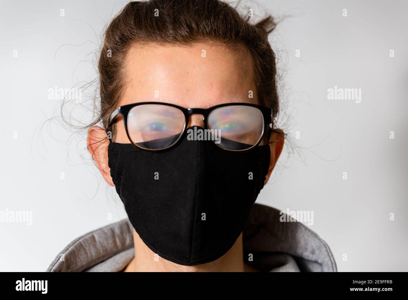 Giovane uomo con occhiali nebbosi causati dall'uso di maschera protettiva per il viso. Misura protettiva durante la pandemia di coronavirus Foto Stock