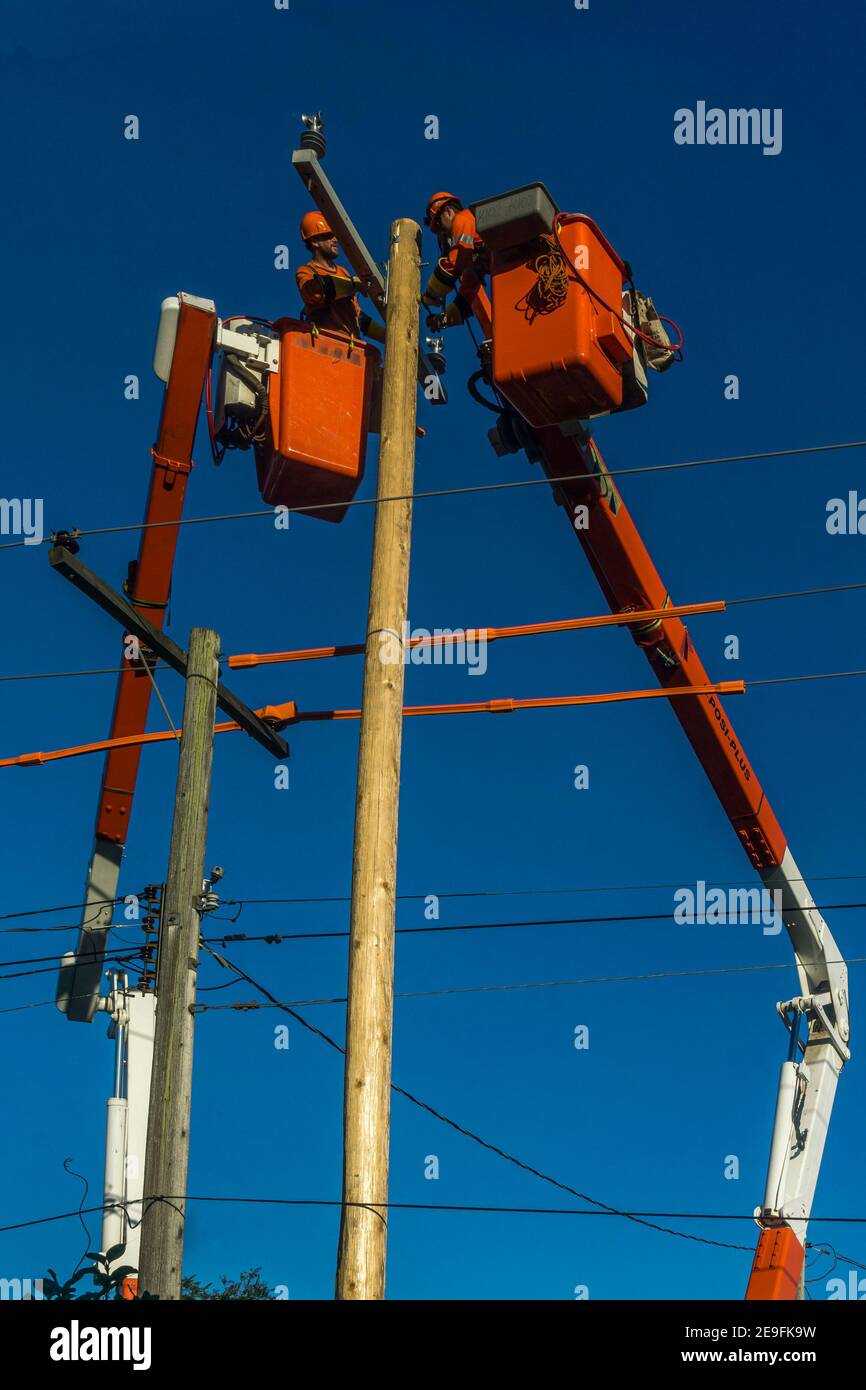 Toronto, Canada, ottobre 2017 - due linemen di potenza in gru che lavorano su palo elettrico e cavo per manutenzione e riparazione Foto Stock