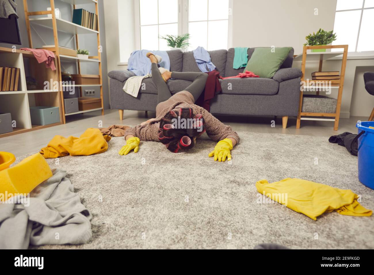 Una casalinga molto stanca è caduta a faccia in giù sul pavimento durante la pulizia il suo appartamento disordinato Foto Stock