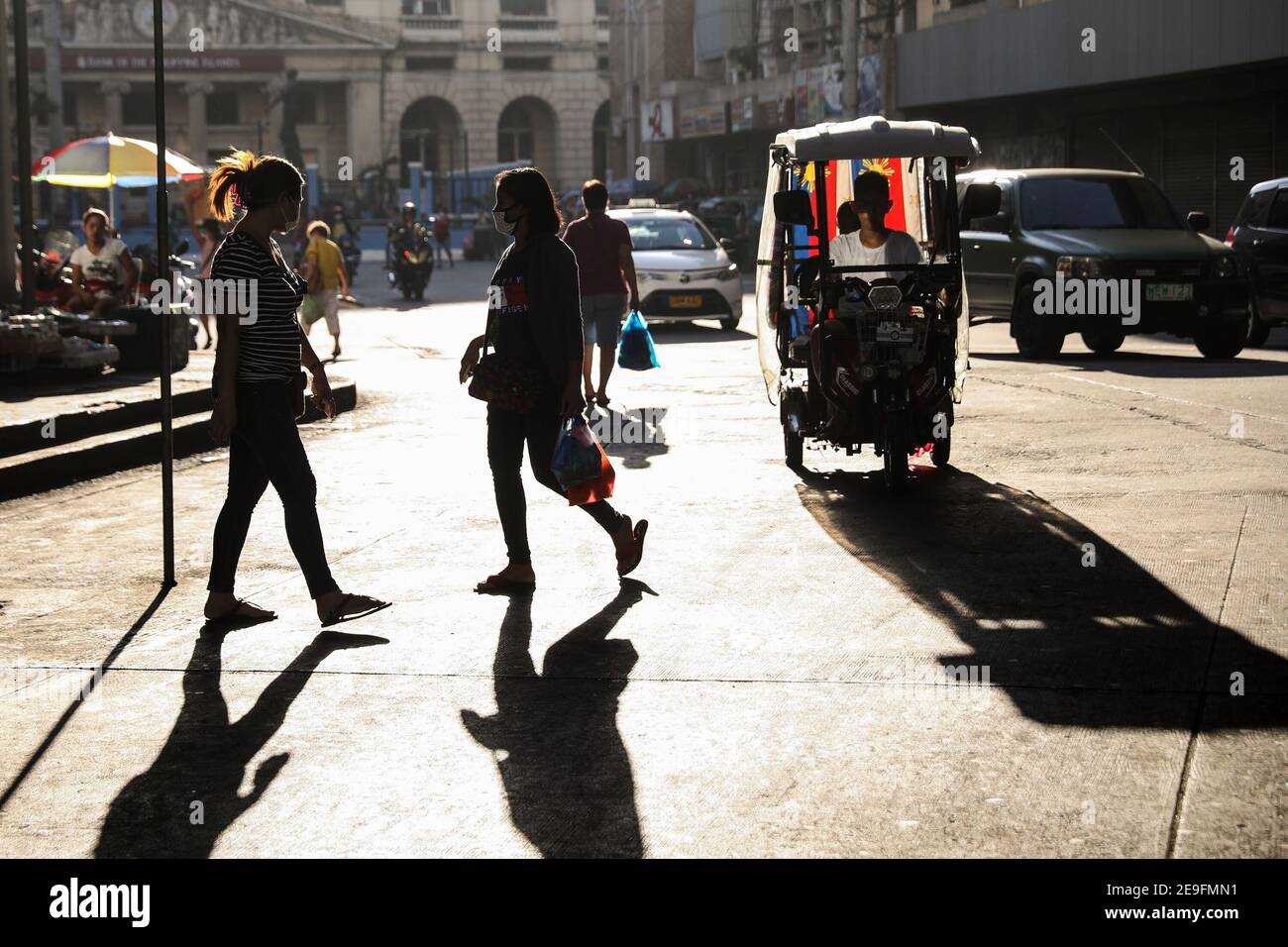 Le persone che indossano una maschera protettiva mentre attraversano una strada nel quartiere cinese di Binondo. Nonostante la quarantena della comunità e l'allontanamento sociale ordinato dal governo a causa della diffusione del coronavirus, molte persone ancora vanno fuori dalle loro case. Manila, Filippine. Foto Stock