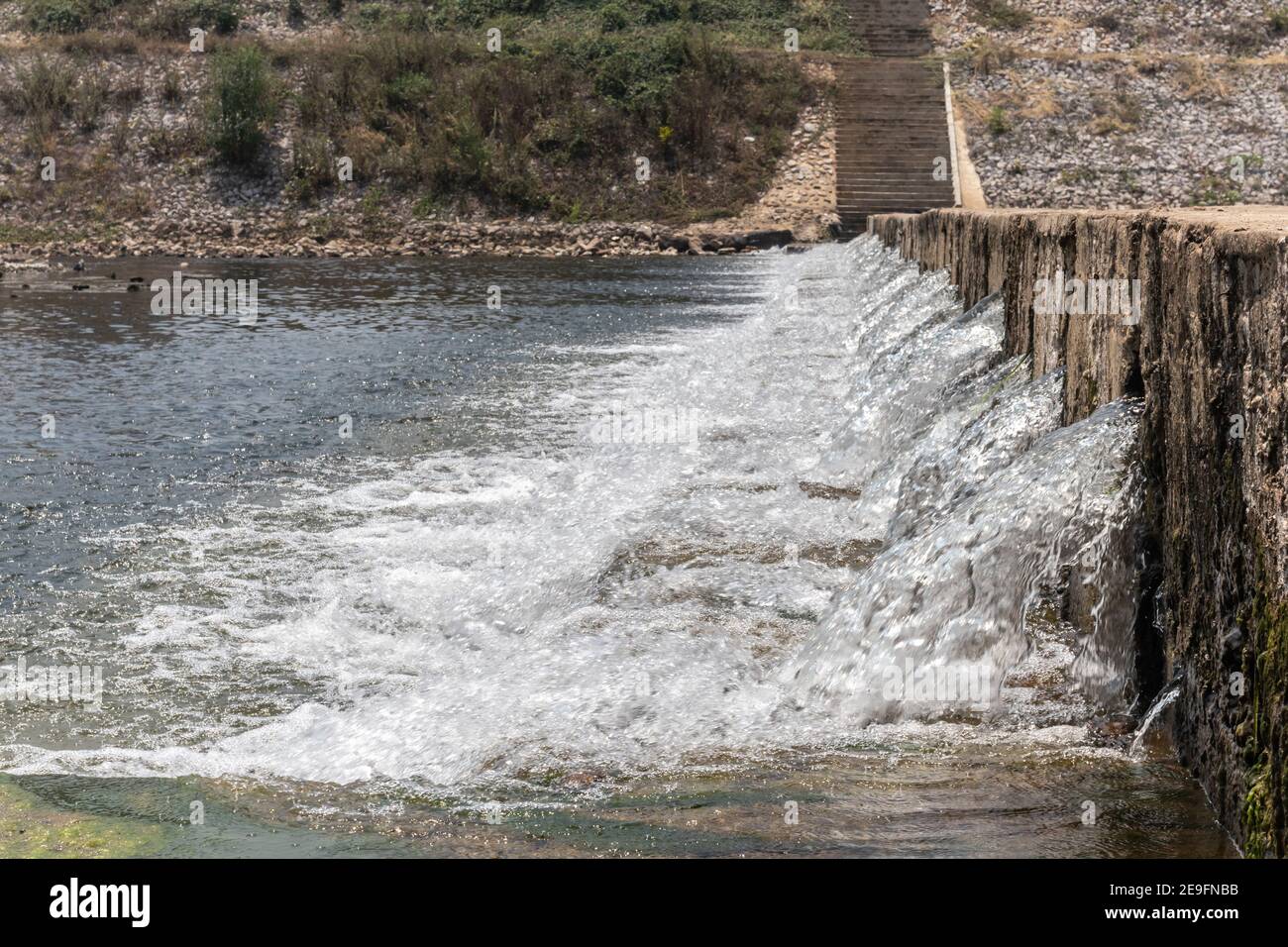 Il flusso d'acqua passa lo stramazzo dal livello superiore al livello inferiore del torrente laterale del fiume. Il weir forma una piccola cascata. Foto Stock