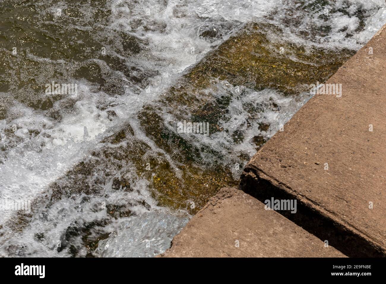 Il flusso d'acqua passa lo stramazzo dal livello superiore al livello inferiore del torrente laterale del fiume. Il weir forma una piccola cascata. Foto Stock