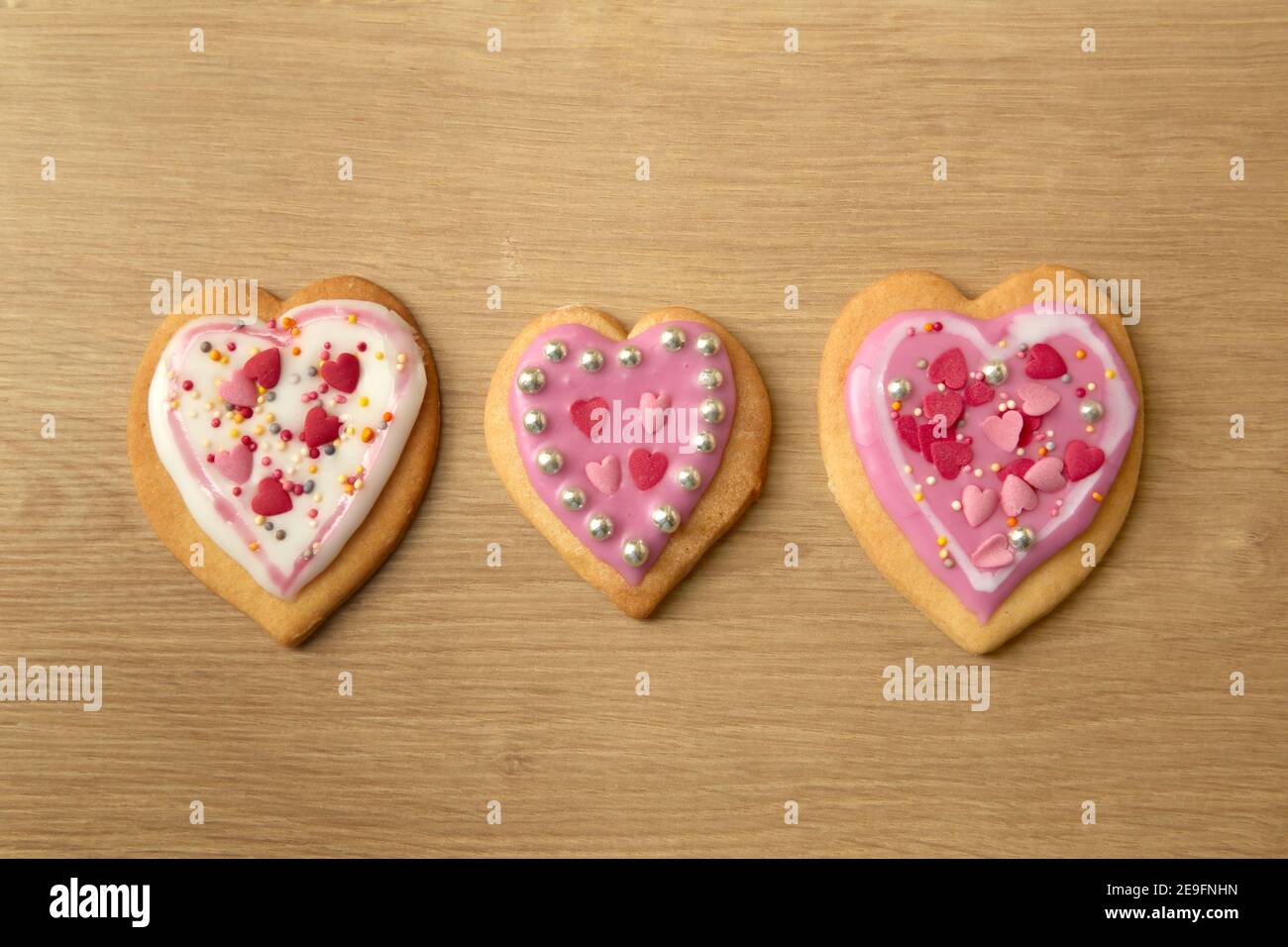 Una fotografia di tre biscotti a forma di cuore dall'alto, sfondo del piano di lavoro della cucina. Foto Stock