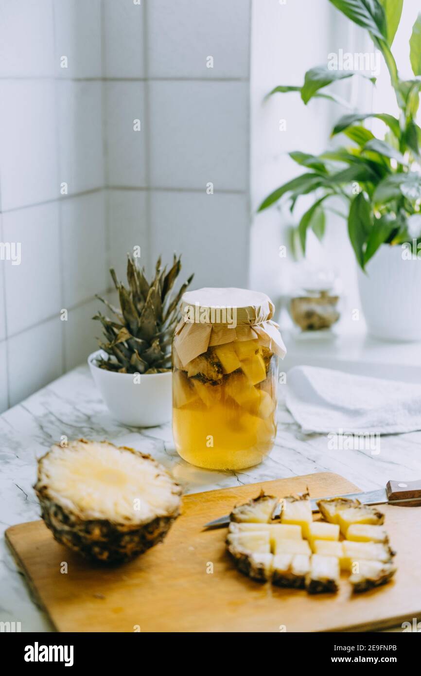Kombucha fermentato ananas bere tepache. Processo di cottura della bevanda di ananas probiotica superfood fatta in casa. Bevi il vasetto e l'ananas a fette a casa Foto Stock