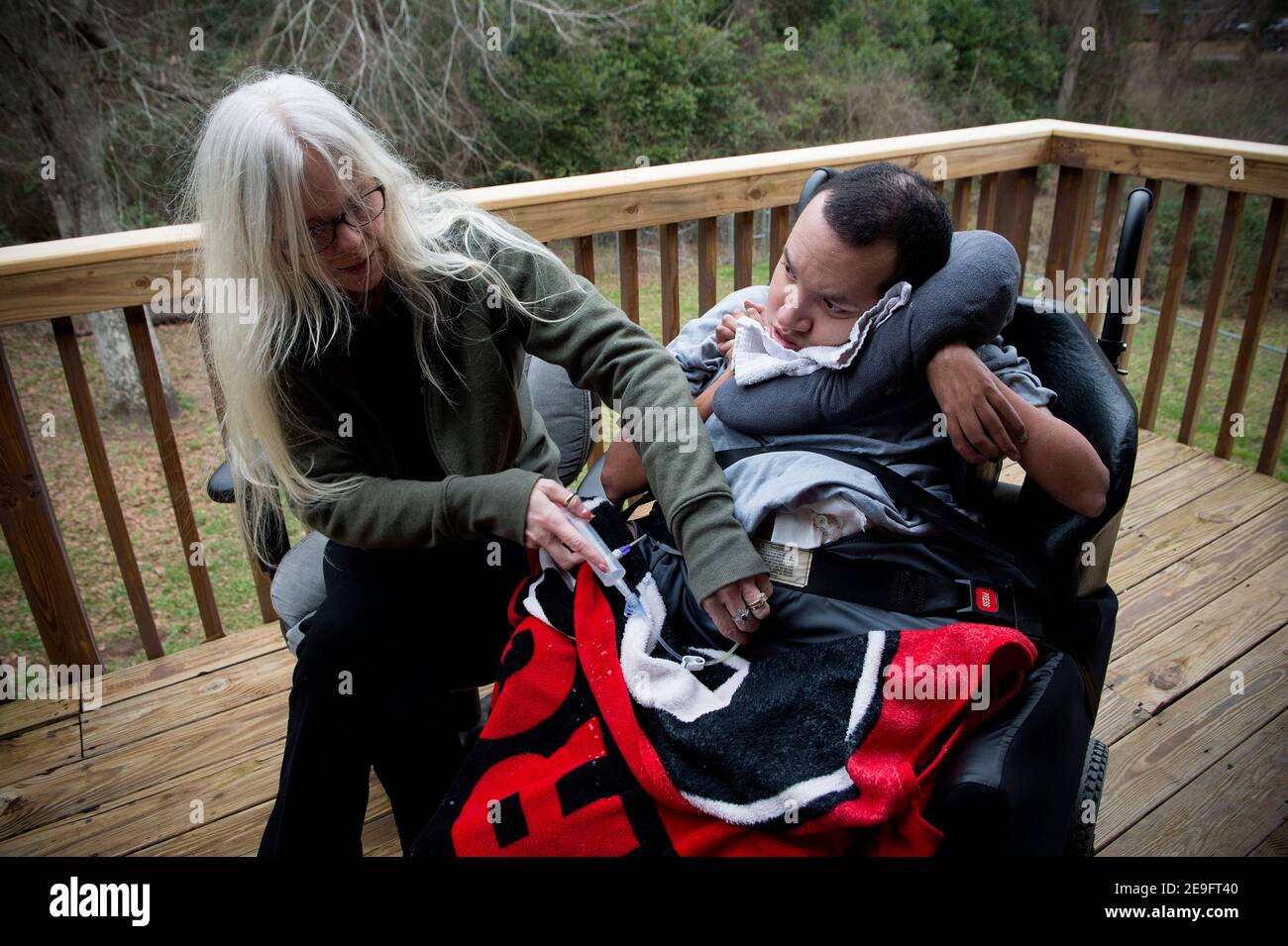 Byron, Georgia, Stati Uniti. 4 Feb 2021. LISA ARCHIBALD si prende cura del fratello John David, profondamente disabile, che si trova a casa sua da oltre 20 anni. John David, 36 anni, è non verbale, quadriplegico e medico fragile a causa della paralisi cerebrale, della policiciria e della displasia. Vive a casa ArchibaldÃs e richiede assistenza 24 ore su 24. Ha convulsioni, malattia polmonare restrittiva e aspirazione silenziosa nei suoi polmoni, che richiede una supervisione costante per prevenire soffocamento.Archibald è stato in grado di prendersi cura di suo fratello nella sua casa con l'aiuto di un patchwork di personale di supporto, finanziato da una rinuncia Medicaid Foto Stock