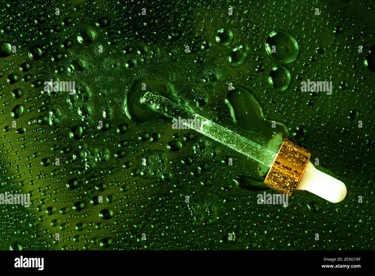 Foglia verde con contagocce di medicina e schizzi d'acqua. Ingredienti per la cura della pelle a base di CBD e piante. Foto Stock