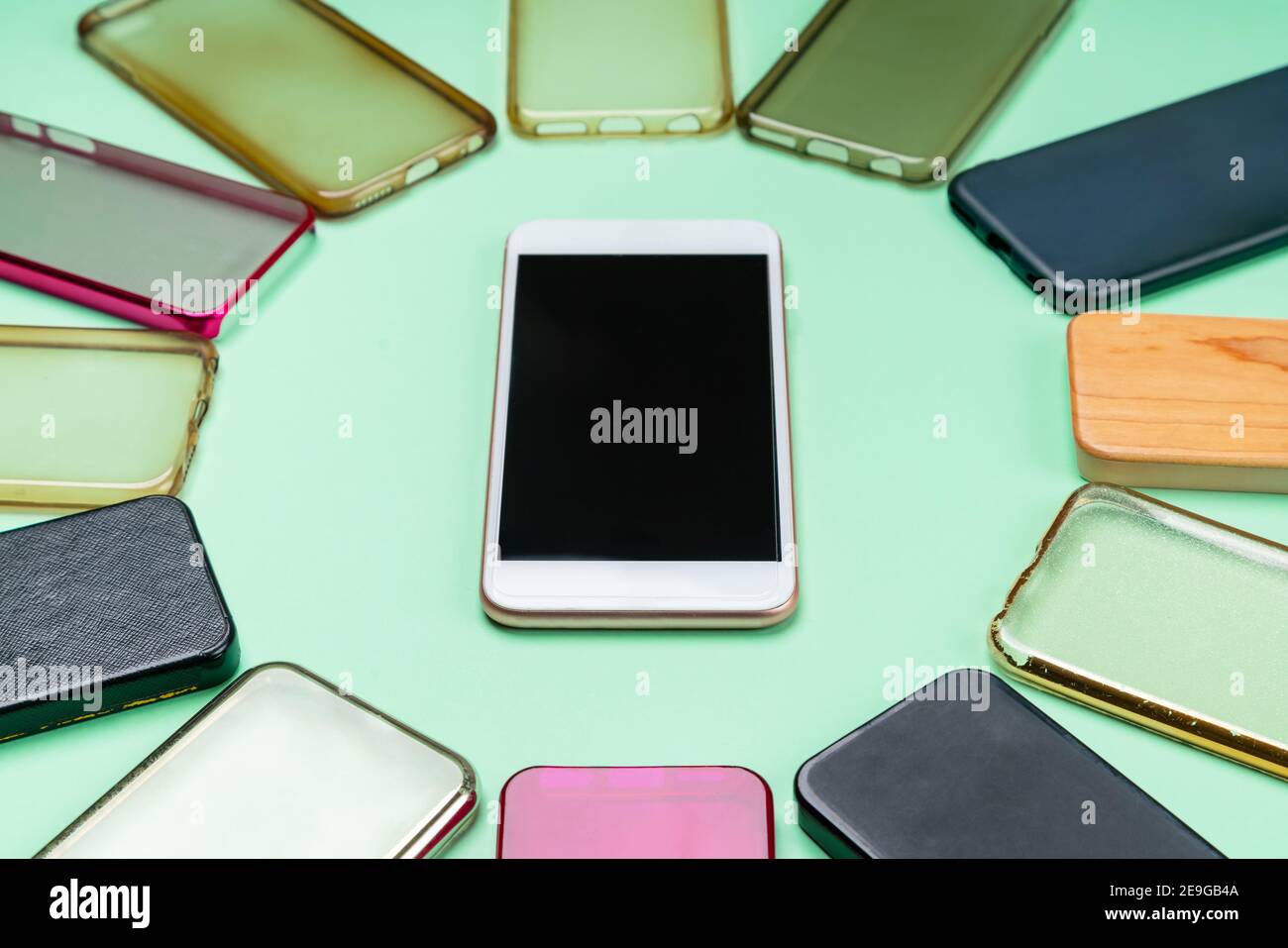 Possibilità di scelta tra cover posteriori in plastica multicolore per telefoni cellulari sfondo verde con uno smartphone sul lato Foto Stock