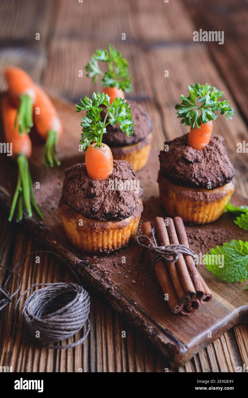 Muffin di carote dolci conditi con crema di cocco e cioccolato, cosparsi di cacao in polvere Foto Stock