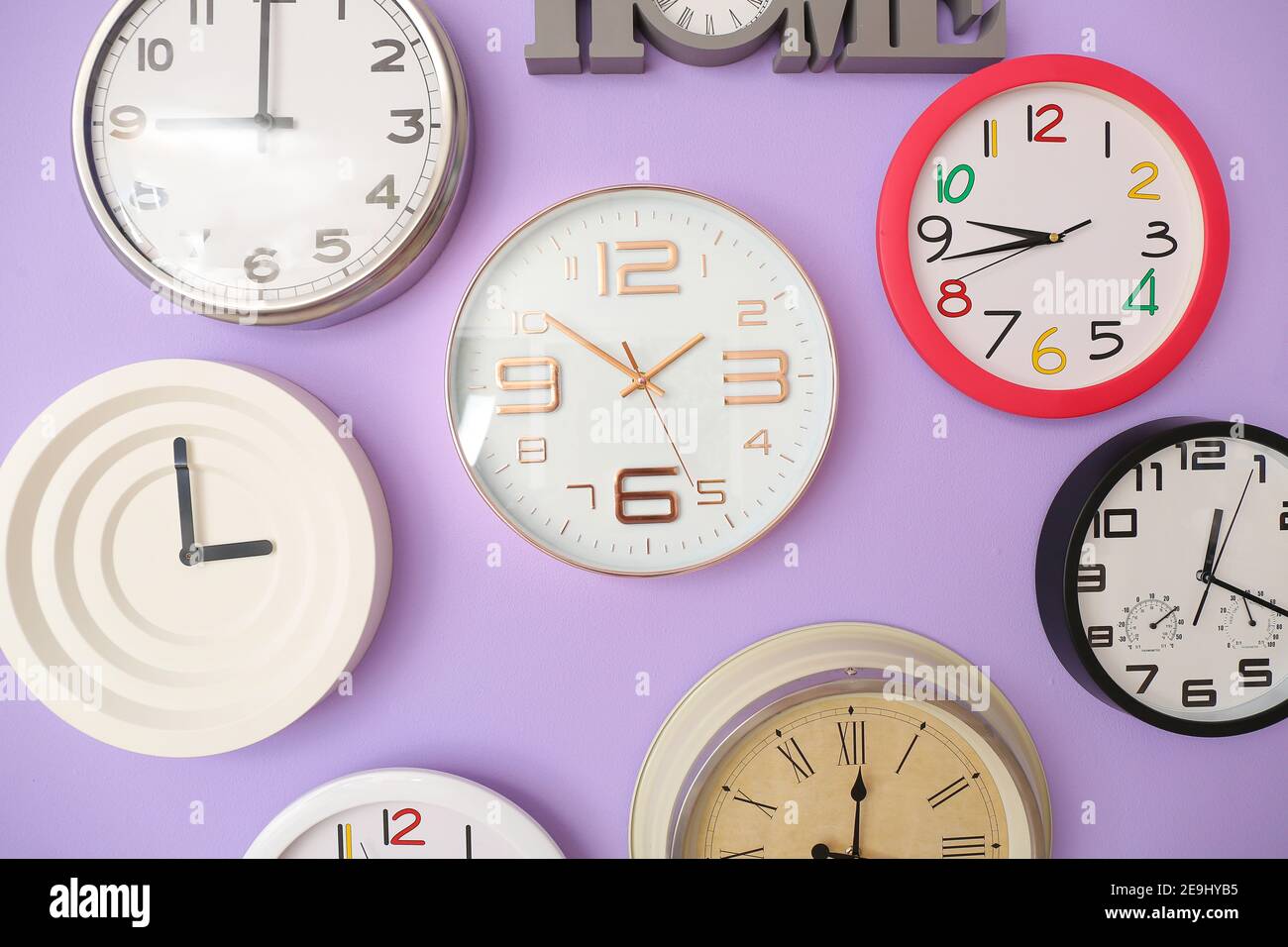 Orologi diversi appesi alla parete colorata Foto Stock