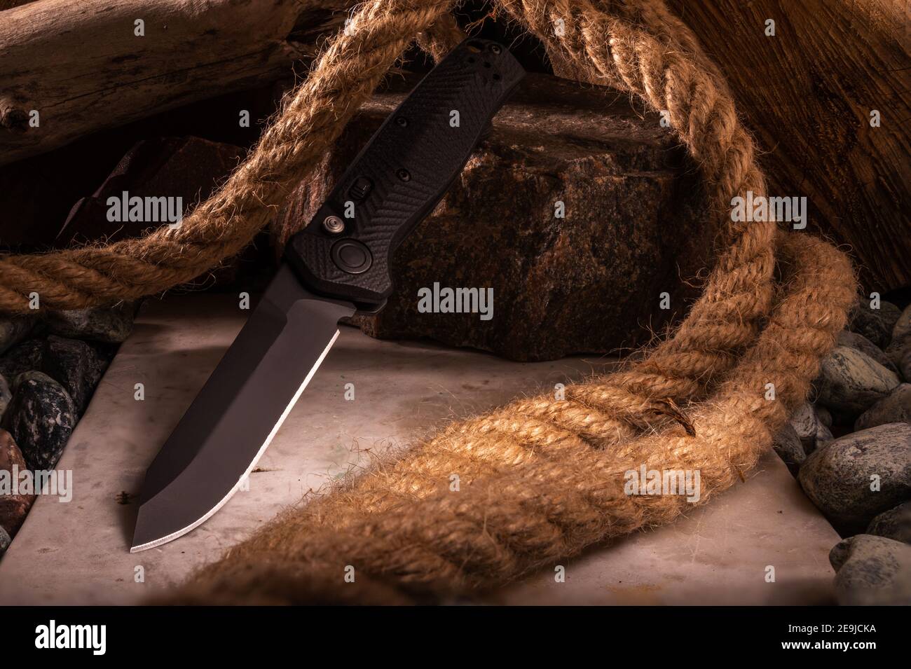 Coltello sullo sfondo di pietre e corda. Foto di un coltello con una grande profondità di campo. In alto. Foto Stock