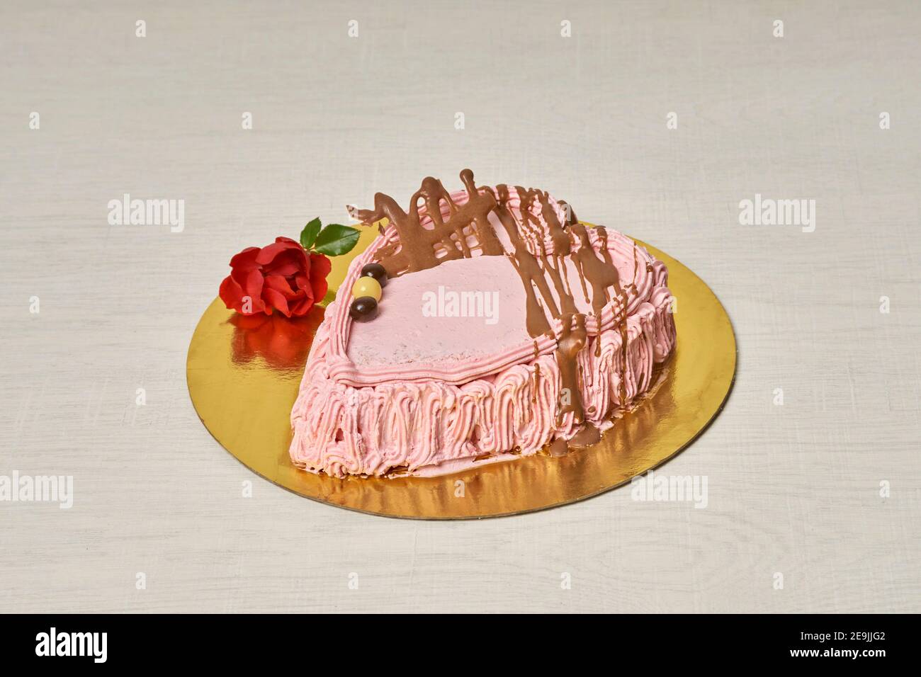 Torta di fragole e crema fatta a mano per San Valentino, a forma di cuore e su base dorata Foto Stock