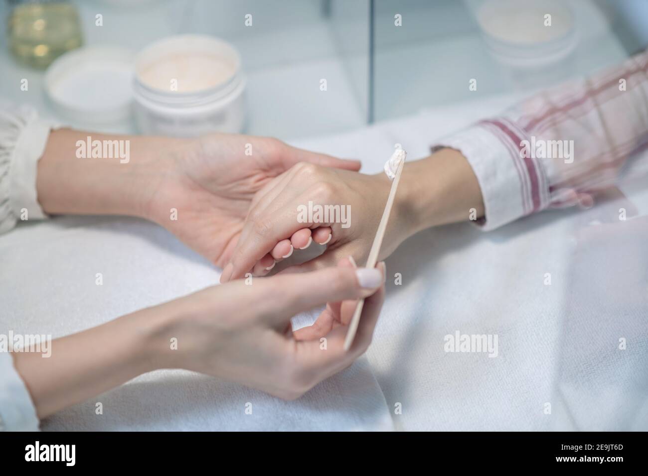 Primo piano immagine di beauticia che aplesa una certa crema al mani dei clienti Foto Stock