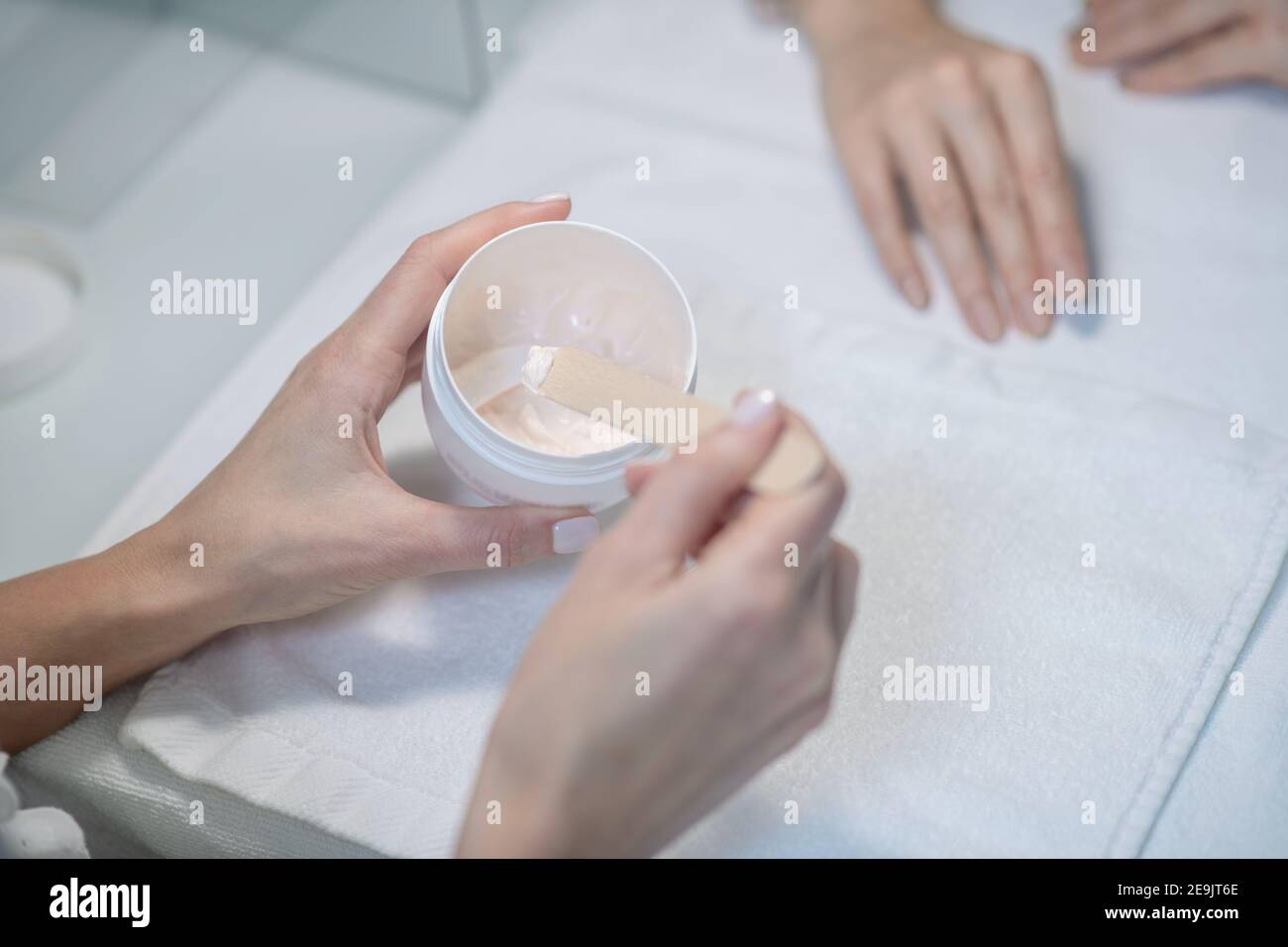 Primo piano immagine di beauticia che aplesa una certa crema al mani dei clienti Foto Stock