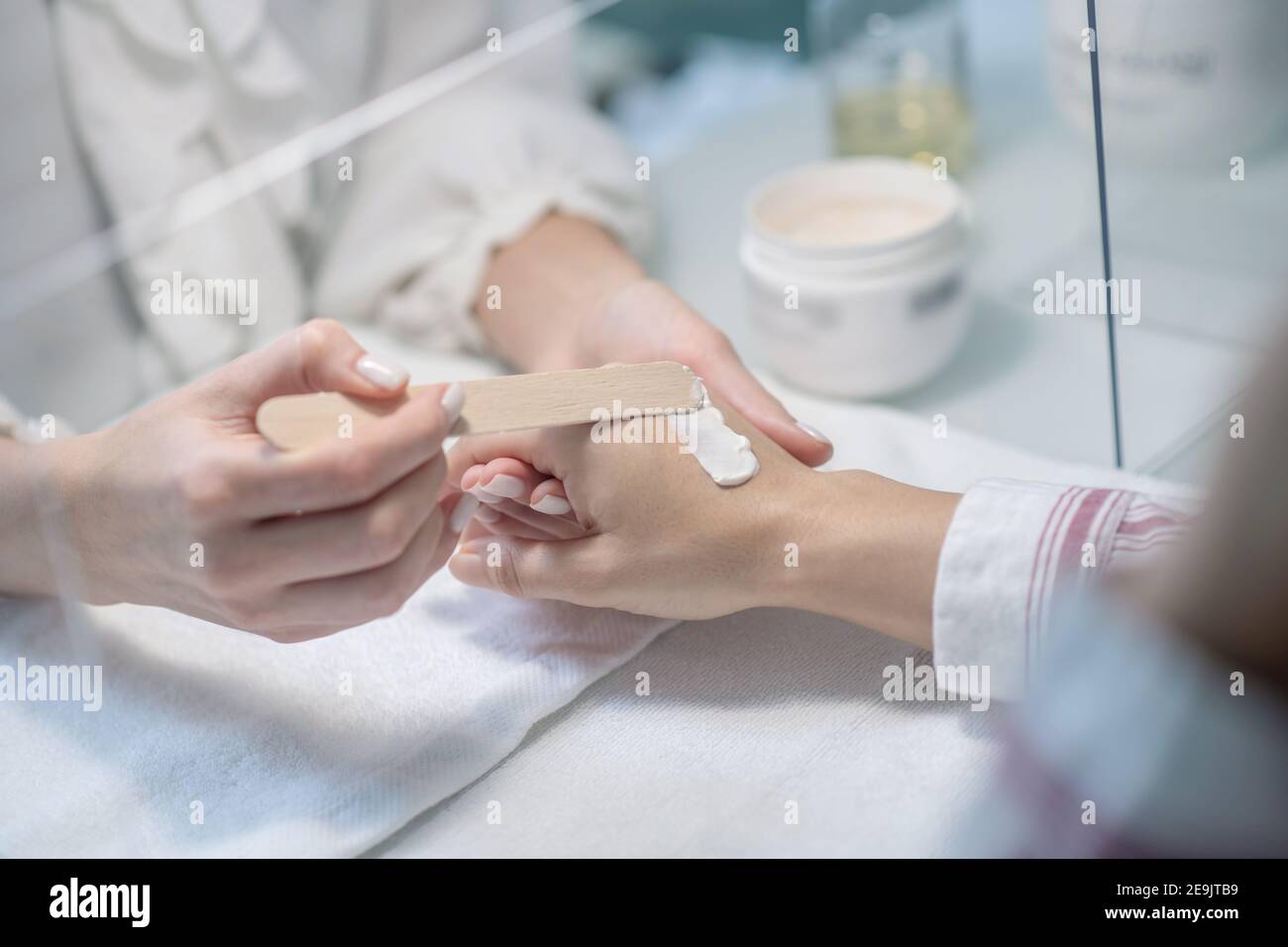 Primo piano immagine di beauticia che aplesa una certa crema al mani dei clienti Foto Stock